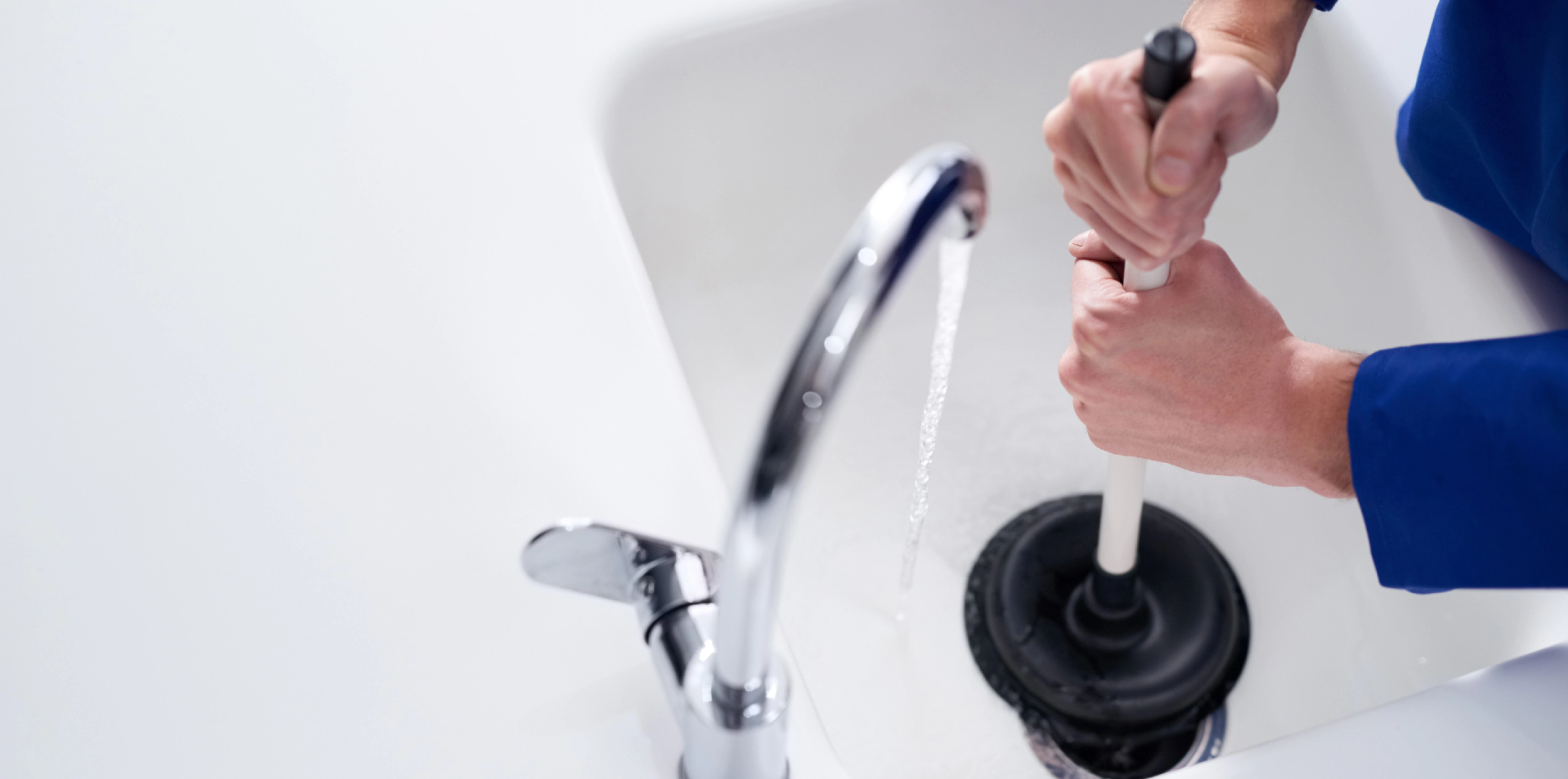 worker cleaning a draing of a white bathtub